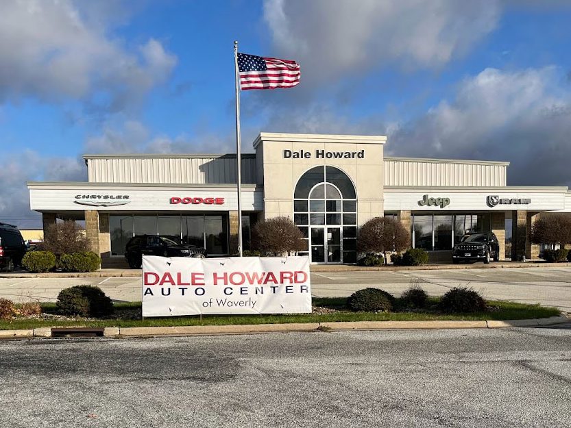Photo of the dealership with the Dale Howard Auto Center of Waverly Banner and American flag in front of the store.